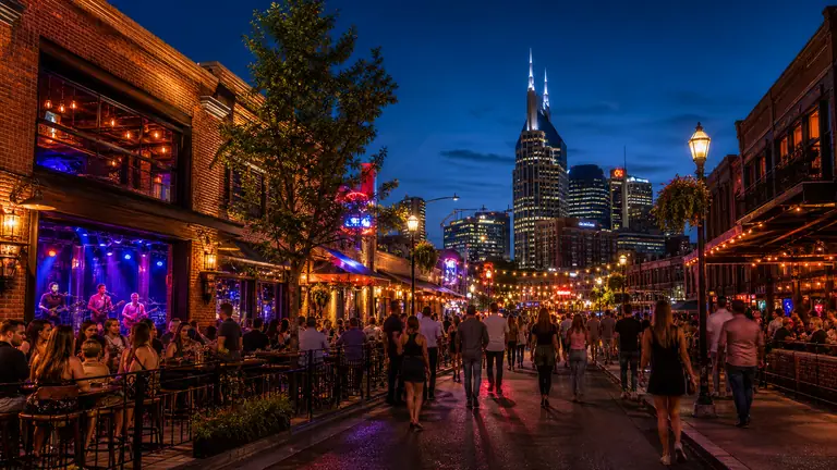Photoreal nightlife district with glowing bars, music-venue energy, and after-dark city street atmosphere