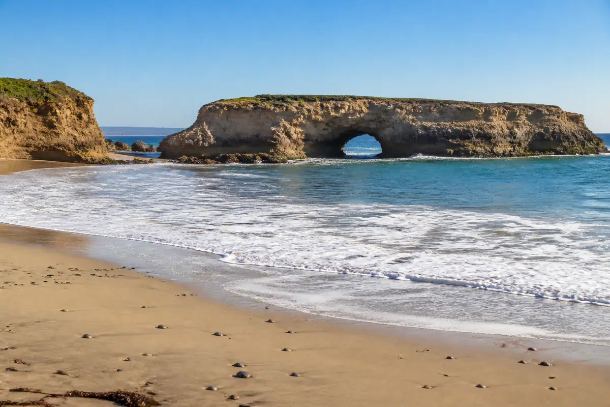 Photoreal travel-editorial view of Natural Bridges State Beach in Santa Cruz, California